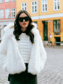 Casaco em pele fake com capuz, fechamento frontal em botões e mangas de cava posta Biamar