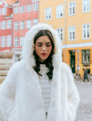 Casaco em pele fake com capuz, fechamento frontal em botões e mangas de cava posta Biamar